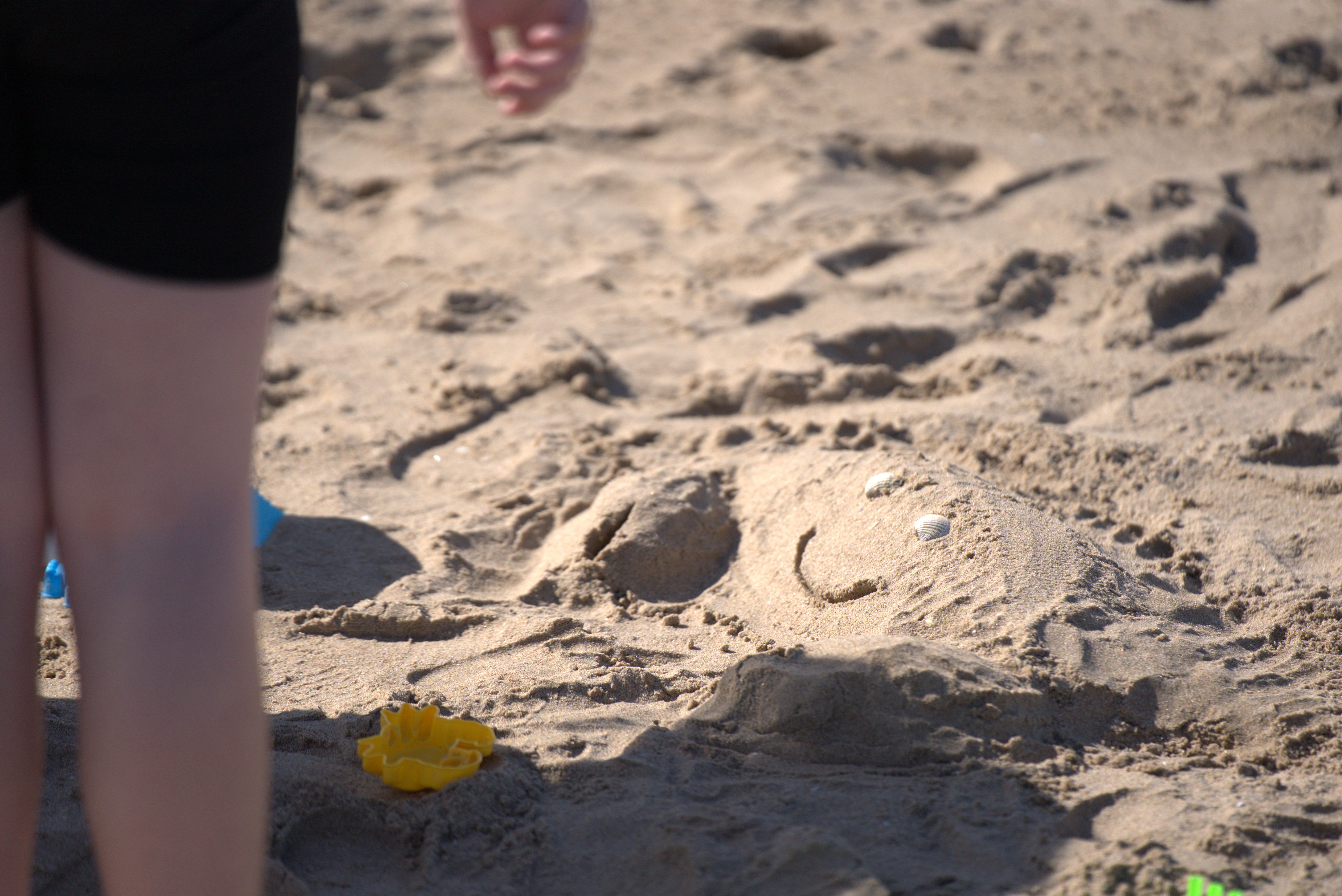A sand sculpture of a smiling crab on a beach