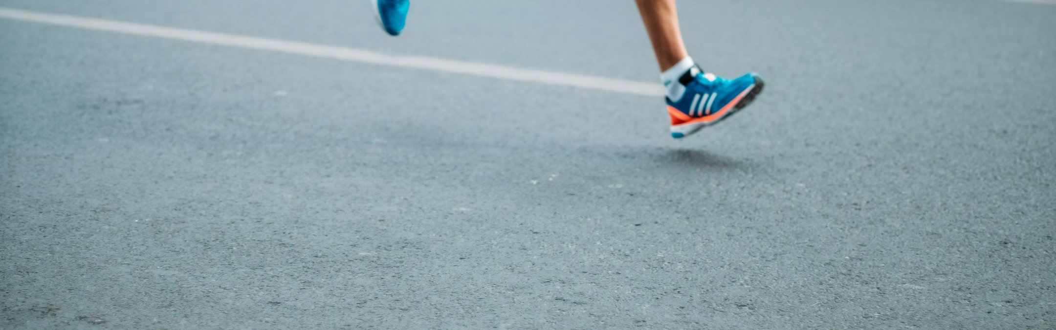 A runner's feet running on a road