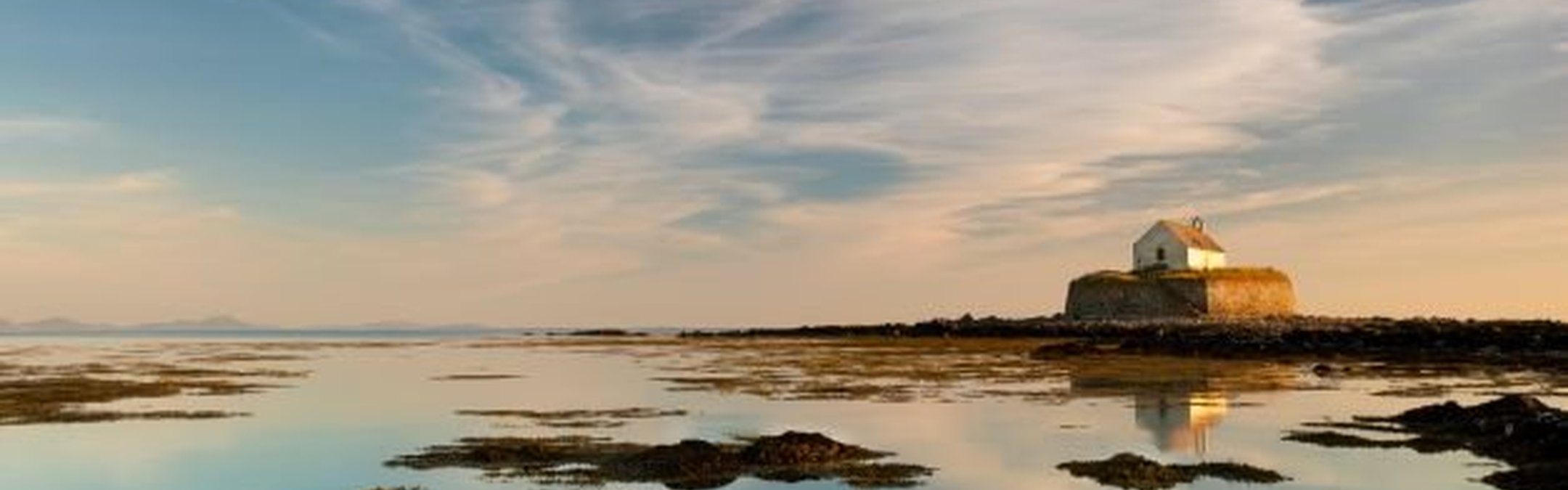 This image shows St Cwyfan's Church, commonly known as the "Church in the Sea," located on the tiny island of Cribinau off the coast of Anglesey, Wales.