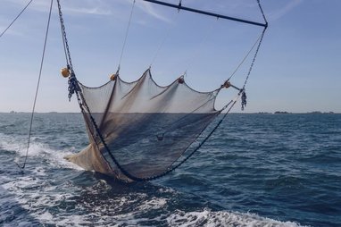 A trawler net is hanging just above the ocean