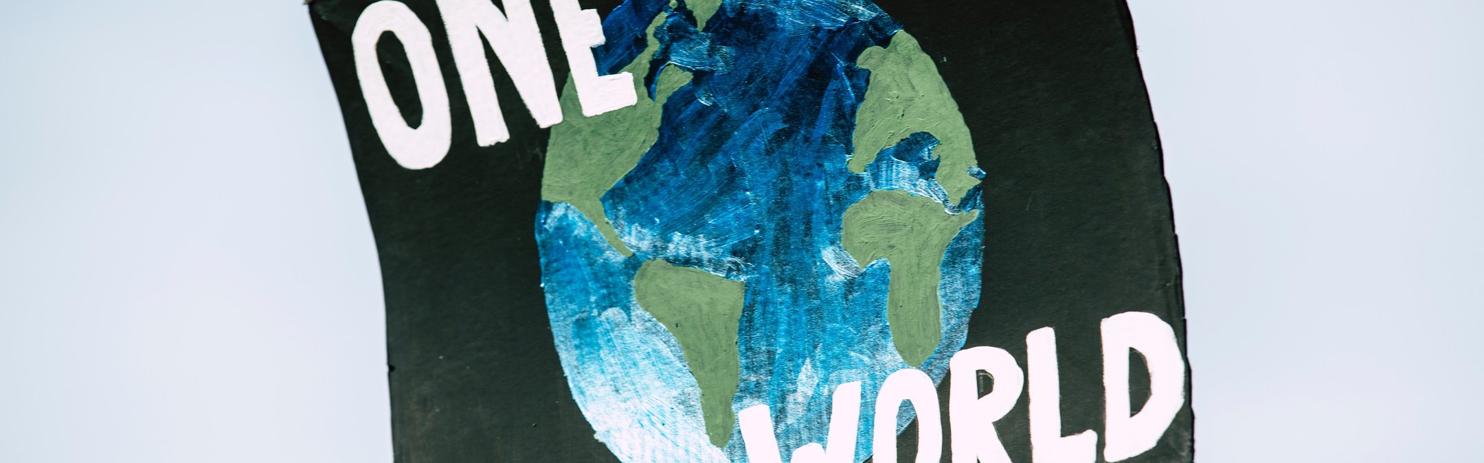 A cardboard campaign sigh that reads "One World" and an image of the Earth in the middle
