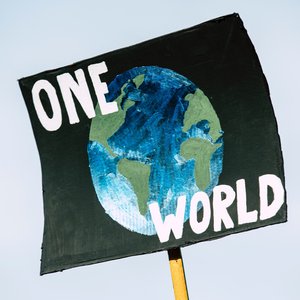 A cardboard campaign sigh that reads "One World" and an image of the Earth in the middle