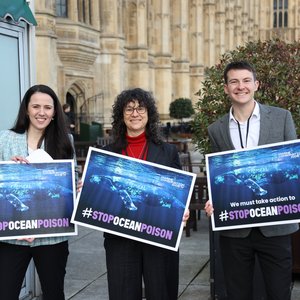 The Marine Conservation Society's CEO and two members of our policy team stand outside parliament holding placards reading 'stop ocean poison'