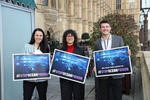 The Marine Conservation Society's CEO and two members of our policy team stand outside parliament holding placards reading 'stop ocean poison'