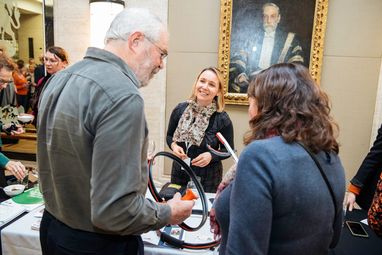 A man and a woman speaking with a smiling volunteer at a Marine Conservation Society display table. The man and women are holding litter picking items that were on the table.