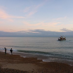 people on Hastings beach with a boat in the water