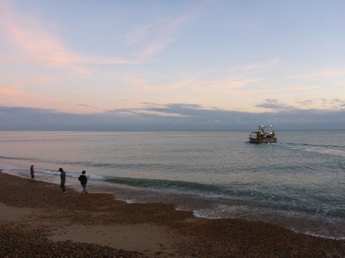 people on Hastings beach with a boat in the water