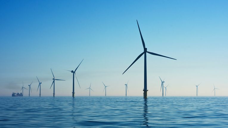 Wind turbines in water at Rampion Offshore Wind Farm, United Kingdom, with blue skies above the water