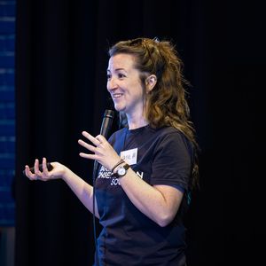 A woman holding a microphone. She is wearing a Marine Conservation Society t-shirt