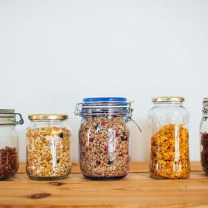 A row of glass jars on a shelf filled with different types of cereal