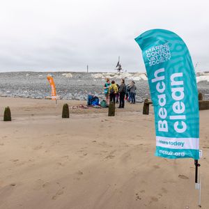 A beach with a flag in the foreground that reads "Marine Conservation Society Beach Clean"
