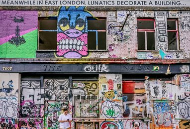 An urban building in Hackney Wick, East London, completely covered in vibrant graffiti, tags, and street art