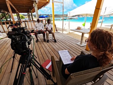 A man and child are sitting on chairs with a camera pointing at them