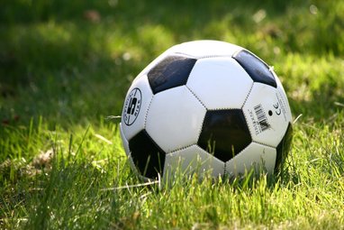 A classic black and white stitched soccer ball resting on green grass.