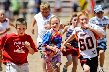 A group o children running on a race track. They are participating in a race