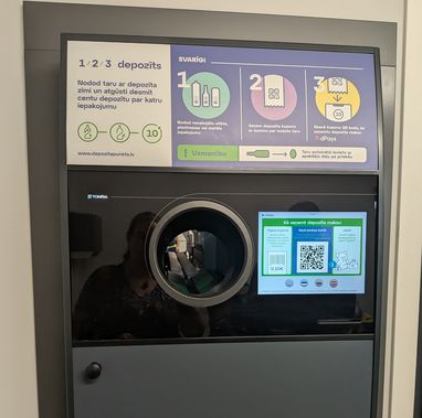 A shot of a reverse vending machine at the Deposit Return Centre in Latvia. A description of how to use it is clear on the top of the machine.