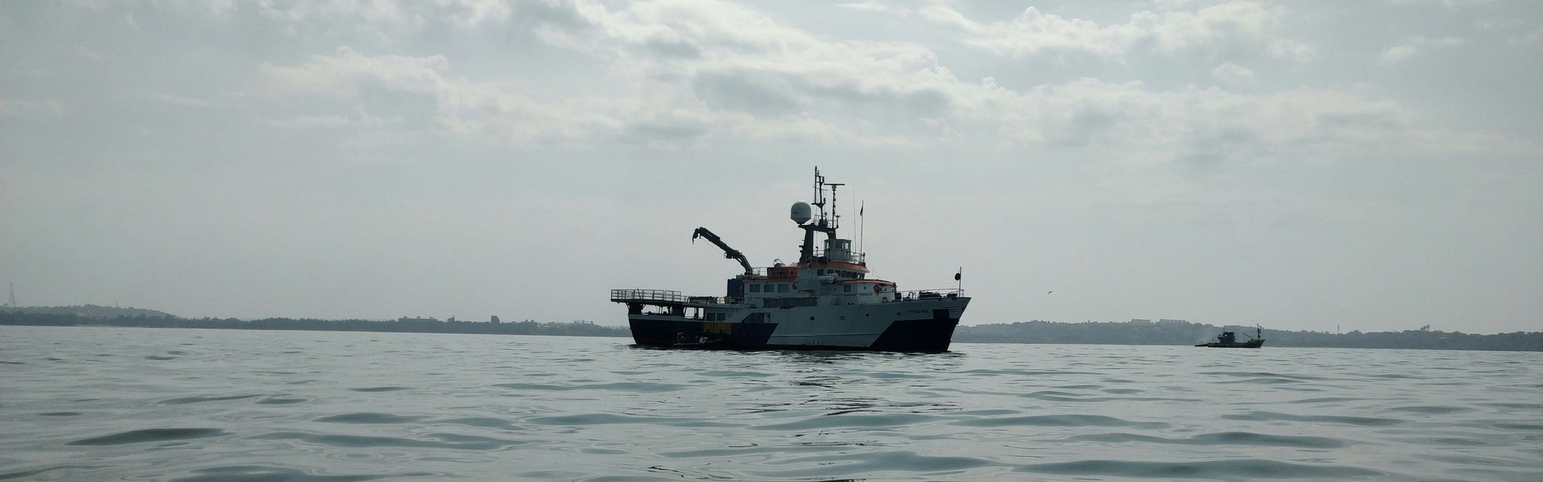 A small white fishing boat is photographed floating in the sea