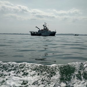 A small white fishing boat is photographed floating in the sea