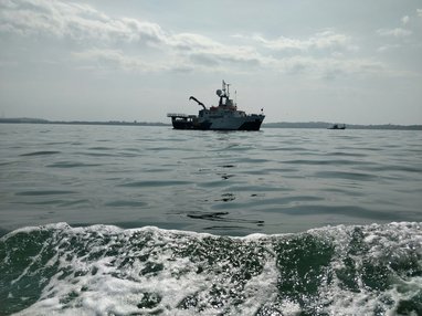 A small white fishing boat is photographed floating in the sea