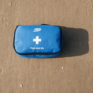 A blue first aid kit on the sand