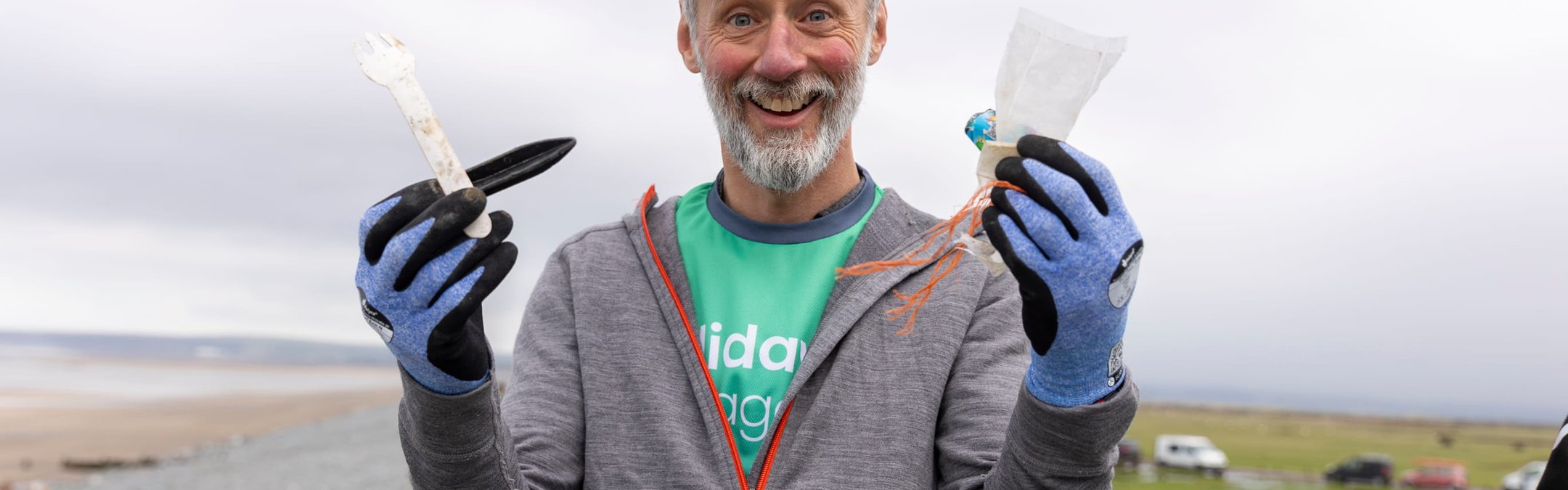 A man showing the camera pieces of debris found on the beach. He is holding a plastic fork, an oyster peg, some string, a popper and a plastic wrapper