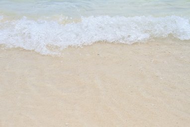 A white snay beach with waves breaking at the top of the image